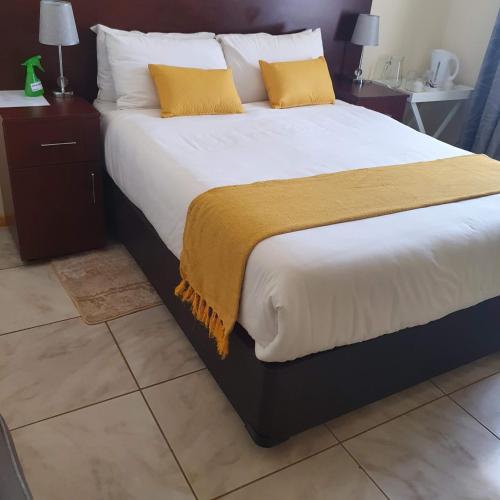 KanyeThokgamo Bed and Breakfast的一张配有白色床单和黄色枕头的大床