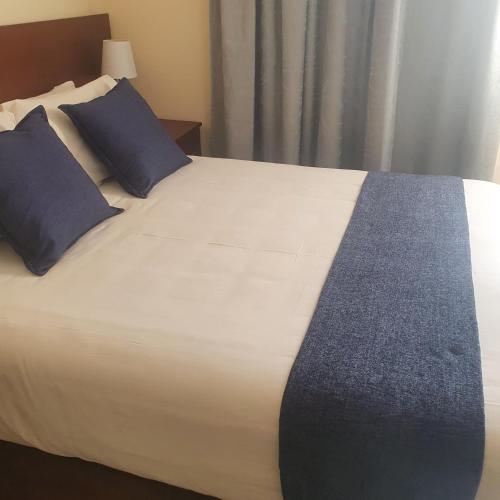 KanyeThokgamo Bed and Breakfast的一张大白色的床,里面配有蓝色枕头