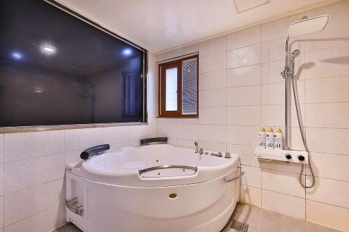 首尔Flower Hotel的白色的浴室设有浴缸和淋浴。