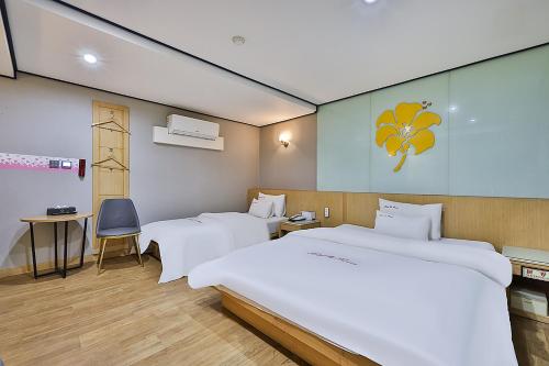 首尔Flower Hotel的一间卧室配有两张床、一张桌子和一把椅子