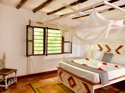 瓦塔穆Nyumba Malkia at Tembo Village的一间卧室配有一张带蚊帐的床