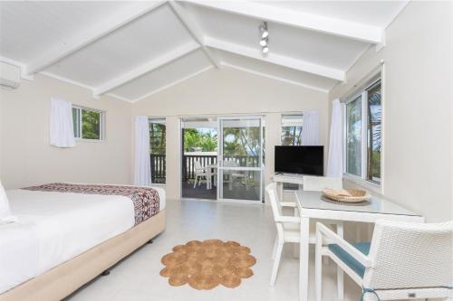 拉罗汤加Muri Lagoon View Bungalows - Hillside Bungalow的一间卧室配有一张床、一张书桌和一台电视