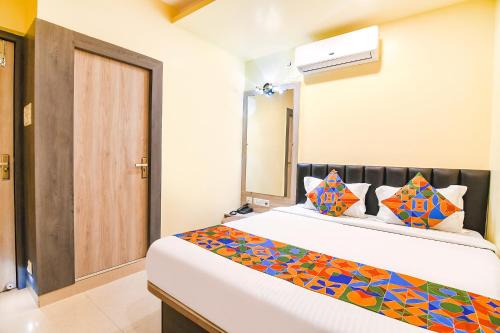 加尔各答FabHotel Bypass View的卧室配有一张带彩色枕头的大型白色床。