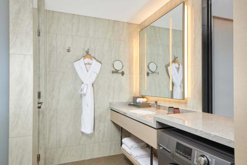长春长春保利万怡酒店的浴室配有盥洗盆、浴袍和淋浴