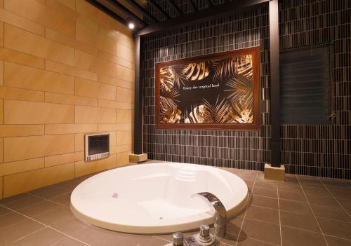 香芝市ホテルウォーターゲート香芝的带浴缸的浴室,墙上配有海报