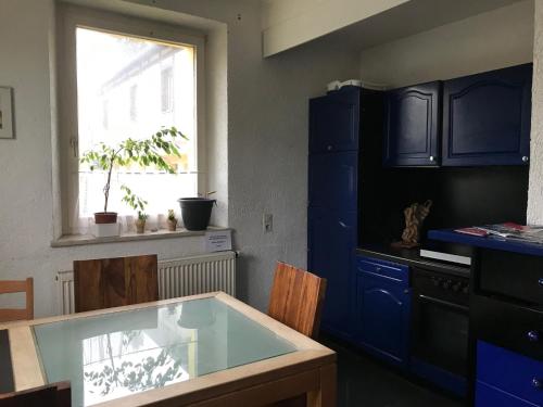 希尔沙伊德德恩哈尔德特宾馆的厨房配有蓝色橱柜、桌子和窗户。