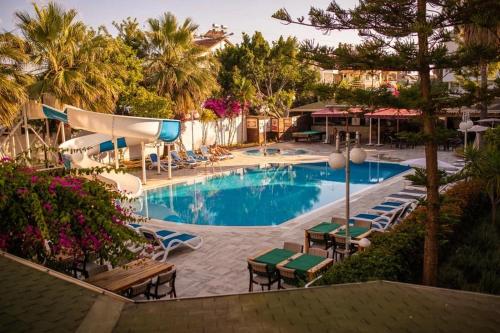 锡德Akalia Suite Hotel & SPA的一个带桌椅的游泳池,棕榈树