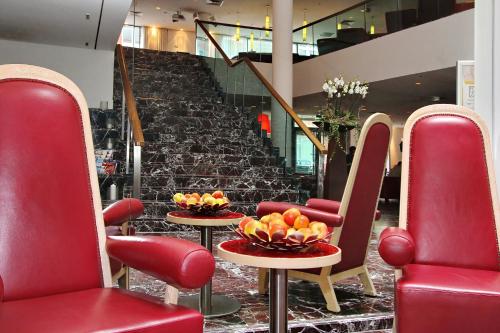 汉堡ARCOTEL Rubin Hamburg的大堂设有红色椅子和桌子,并备有水果