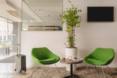 埃因霍温Crown Hotel Eindhoven Centre的两张绿色椅子和一张桌子,上面有盆栽植物