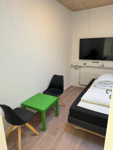 奥尔堡Italian Rooms 7的客房设有一张床和一张绿色的桌子和椅子。