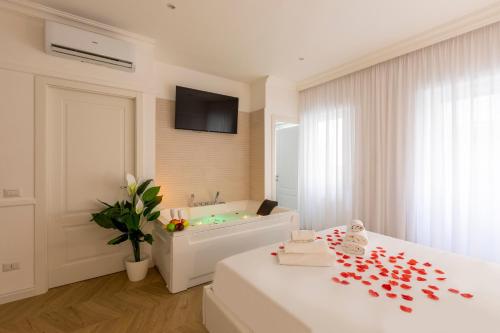 罗马FARNESINA SUITE的一间白色卧室,配有浴缸和一张红色花瓣床