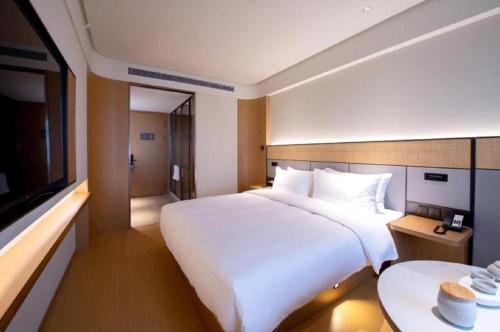 北京JI Hotel Beijing Dazhongsi的卧室配有一张白色大床和电视。