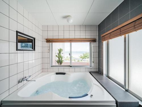 石垣岛The Beach Terrace Hotel AO Ishigaki的带浴缸的浴室和窗户