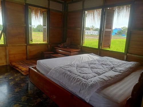 Phumĭ Puŏk ChăsMeta Homestay的一间带一张大床的卧室,位于带窗户的房间内