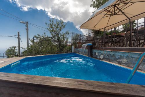 阿杰罗拉尼多德利雷酒店的一座蓝色游泳池,旁边是一座建筑,上面有一把遮阳伞