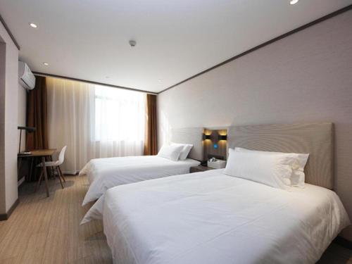 合肥Hanting Hotel Hefei Baoye Dongcheng Plaza的配有白色床单的酒店客房内的两张床