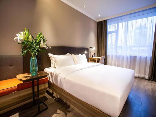洪家楼Hanting Premium Hotel Jinan Shandong University Central Campus的卧室配有白色的床和花瓶