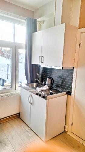 利勒哈默尔Sentrumsnær leilighet - K1的厨房配有白色橱柜、水槽和窗户。