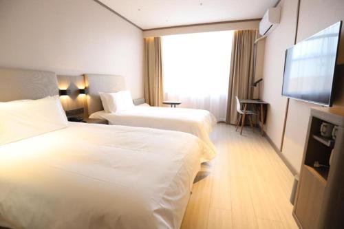 珲春Hanting Hotel Hunchun Railway Station的酒店客房设有两张床和一台平面电视。