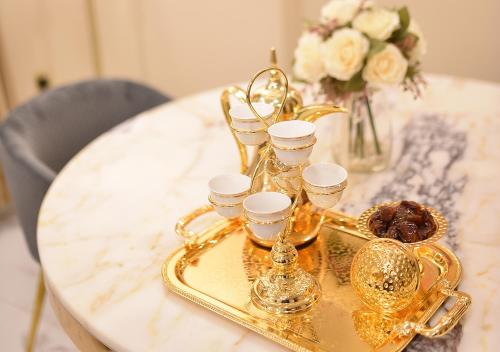 科威特الدانة للشقق الفندقية的桌上装有杯子和玻璃杯的金盘