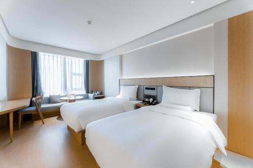 JinzhuzhenJi Hotel Guiyang Guanshan Lake High-Tech Zone的酒店客房配有两张床和一张书桌