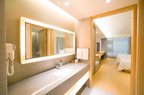 花都Ji Hotel Guangzhou Baiyun Airport的一间带水槽和镜子的浴室以及一张床
