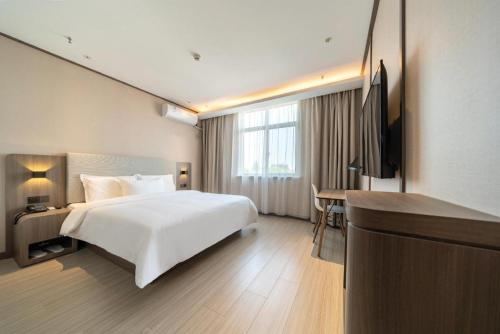 Ssu-t'uan-ts'angHanting Hotel Shanghai Safari Park Nanzhu Road的一间酒店客房,配有一张白色的床和一张书桌