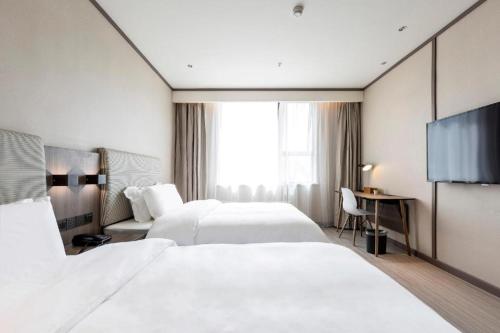 GuodianHanting Hotel Zhengzhou South Longhu Shawoli Metro Station的一间酒店客房,设有两张床和电视