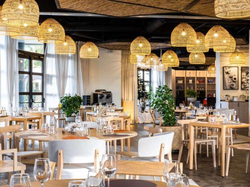 戛纳戛纳曼德里尔美居酒店的餐厅设有桌椅和吊灯。