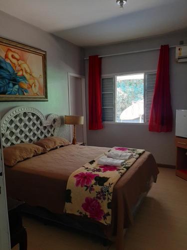 乌巴雅拉Pousada e Museu JK的一间卧室配有床和红色窗帘的窗户