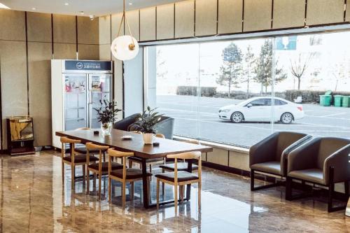鄂尔多斯Hanting Premium Hotel Ordos Kangbashi Scenic的一间配备有桌椅和白色汽车的用餐室