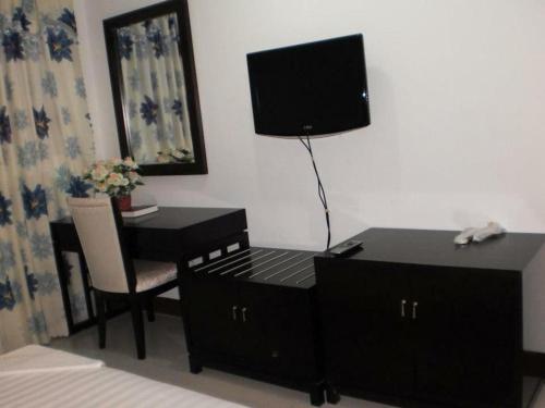杜马格特Asia Novo Boutique Hotel-Dumaguete的一间卧室配有一张桌子和一张带电视的床。