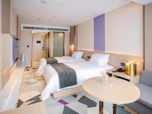 惠州Lavande Hotel Huizhou World Trade Center的酒店客房设有两张床和一张桌子。