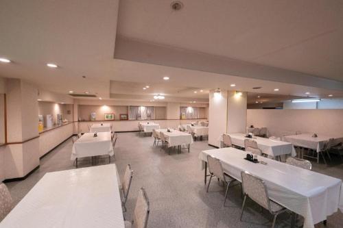 都城市Main Hotel的用餐室配有白色的桌子和白色的椅子