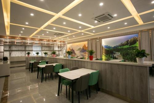 XibeiwanStarway Hotel Changji Qitai Bus Station的一间在客房内配有桌子和绿色椅子的餐厅