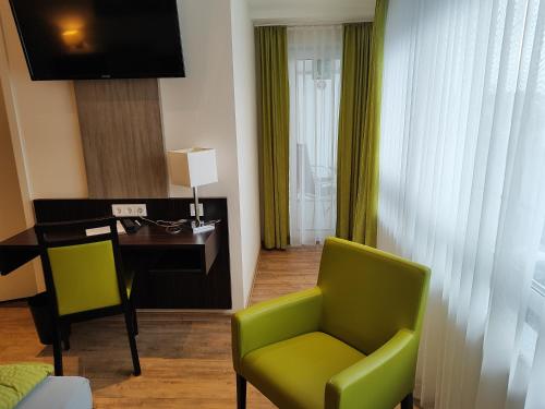 腓特烈港Hotel Gästehaus Stock Zimmer Brotkörble的客厅配有书桌和绿色椅子