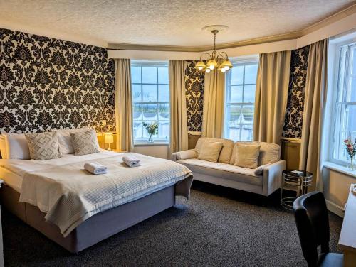 LongtownGraham Arms Inn的一间卧室配有一张床、一张沙发和窗户。