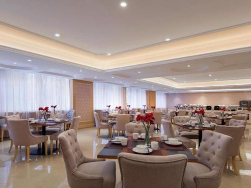 惠州Vienna Hotel Guangdong Huizhou Huabianling Square的一间餐厅,配有桌椅和鲜花