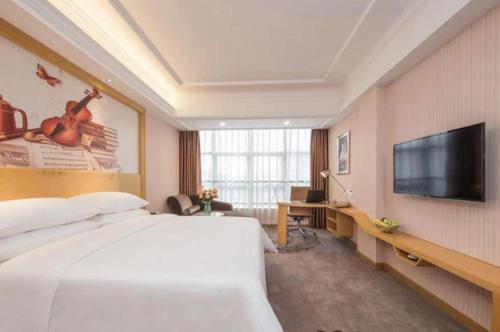 花都Vienna Hotel Guangzhou North Station Huaguoshan Metro Station的一间酒店客房,配有一张大床和一台平面电视