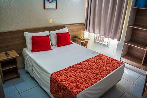 圣若泽杜斯坎普斯圣若泽杜斯坎普斯广场酒店的配有红色枕头的床的酒店客房