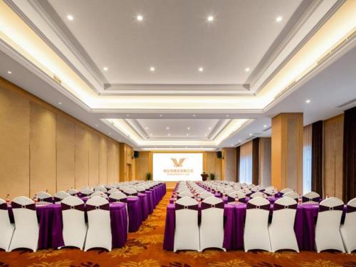 丰都Vienna Hotel Chongqing Fengdu的紫色和白色桌子的房间的一排椅子