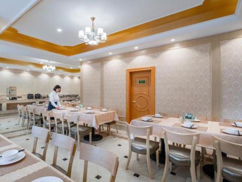 YanglinVienna Hotel Kunming Dianzhong New District的坐在饭厅里的人,有桌椅