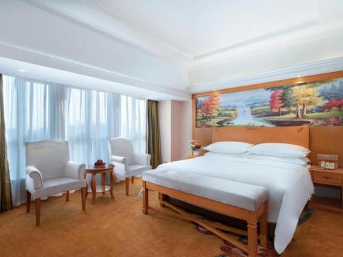 YanglinVienna Hotel Kunming Dianzhong New District的一间卧室配有一张大床和两把椅子