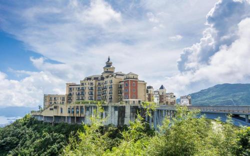 深圳Vienna Hotel Shenzhen Window of the World Qiaochengdong Metro Station的一座带桥的山顶上的大型建筑