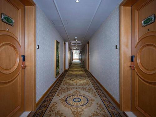 珲春Vienna Hotel Jilin Huichun Yadu Huayuan的走廊设有长长的走廊,铺有瓷砖地板