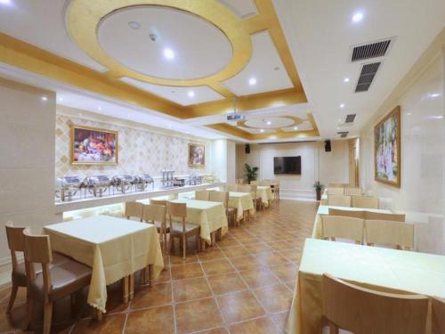 重庆Vienna Hotel Chongqing Jiefangbei Hongyadong的一间设有白色桌椅的餐厅和一间酒吧