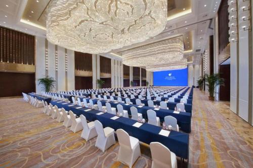 Grand New Century Hotel Zunyi China的一个带椅子和大吊灯的大型宴会厅