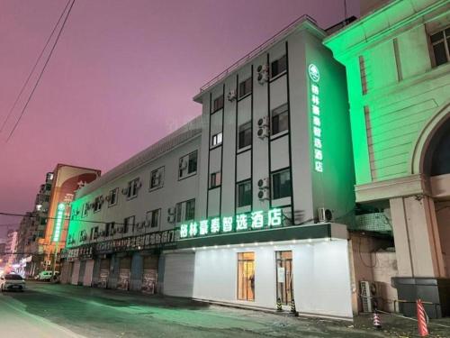 沈阳Green Tree Inn Shenyang Middle Street的建筑的一侧有绿色标志