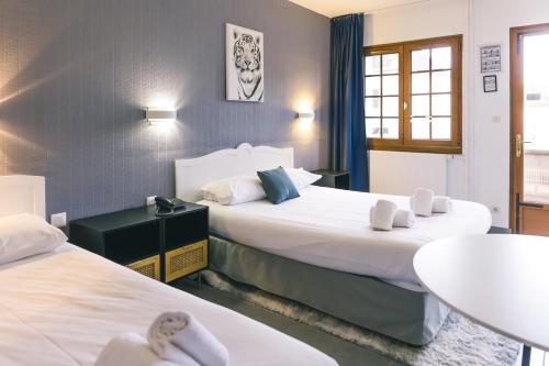蒙蒂尼雷斯LOGIS Hôtel & Restaurant Le Soleil D'or的酒店客房设有两张床和一张桌子。