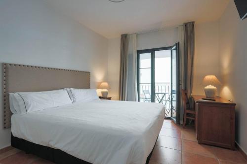 奥尔维拉Hotel Tugasa Sierra y Cal的一间带一张白色大床的卧室和一个阳台
